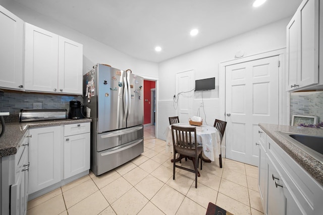 kitchen with stainless steel fridge, light tile patterned floors, and white cabinets