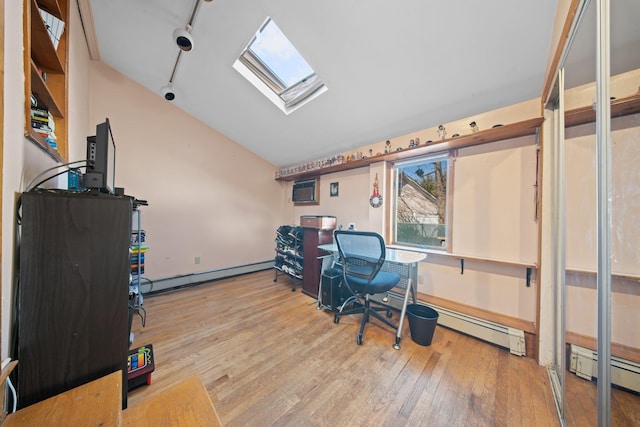 office space with baseboard heating, vaulted ceiling with skylight, light hardwood / wood-style floors, and rail lighting