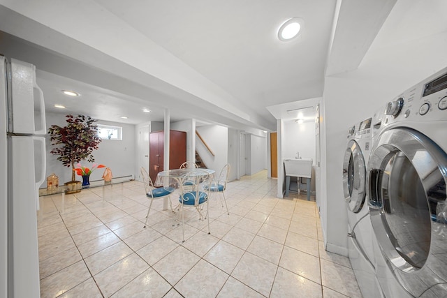 laundry room featuring washing machine and dryer, light tile patterned flooring, and a baseboard radiator