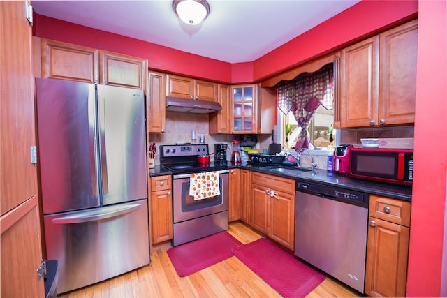 kitchen with stainless steel appliances, tasteful backsplash, sink, and light hardwood / wood-style flooring