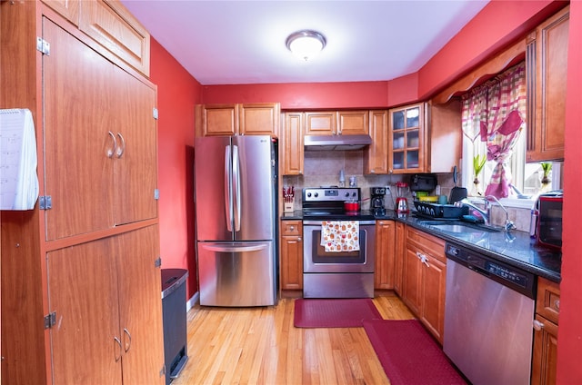 kitchen with tasteful backsplash, sink, stainless steel appliances, and light hardwood / wood-style floors