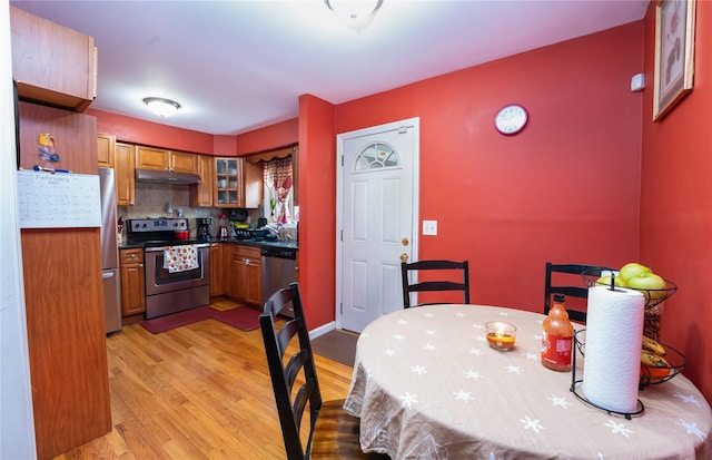 kitchen with stainless steel appliances, sink, backsplash, and light wood-type flooring