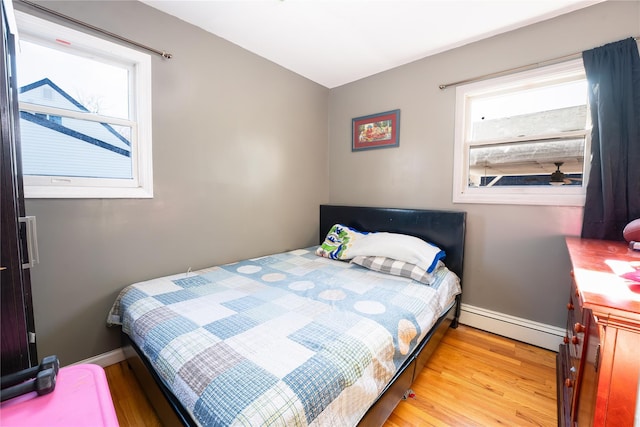 bedroom with a baseboard radiator and light hardwood / wood-style floors