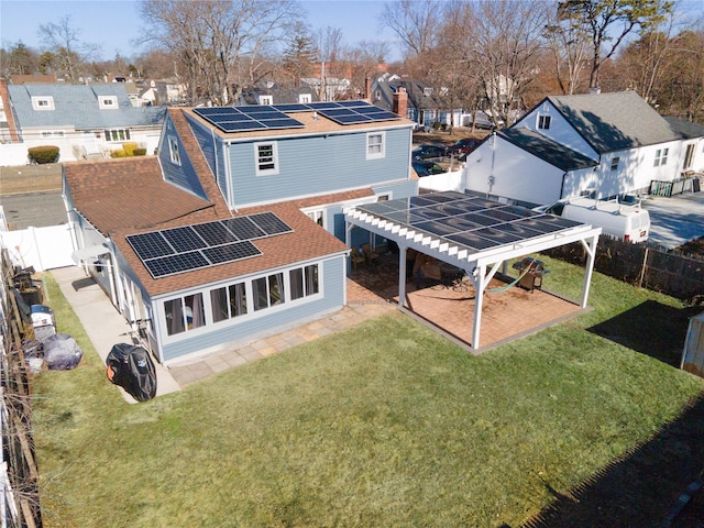 rear view of property with a lawn and solar panels