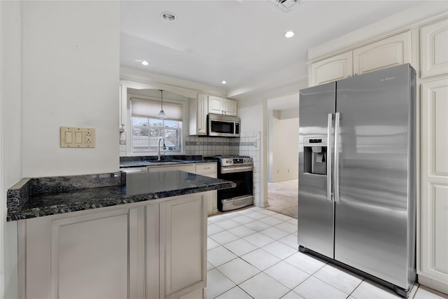 kitchen with appliances with stainless steel finishes, tasteful backsplash, white cabinetry, dark stone counters, and light tile patterned floors