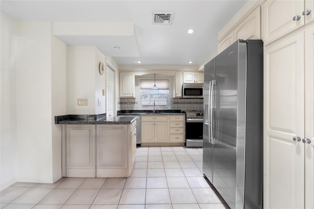 kitchen with sink, tasteful backsplash, light tile patterned floors, appliances with stainless steel finishes, and dark stone counters