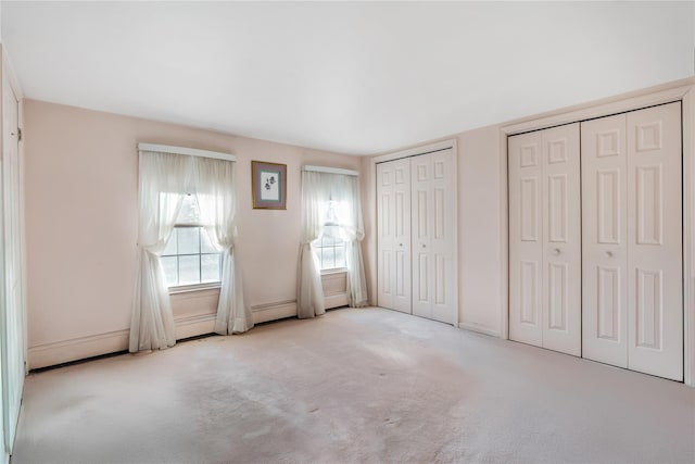 unfurnished bedroom with light carpet and two closets