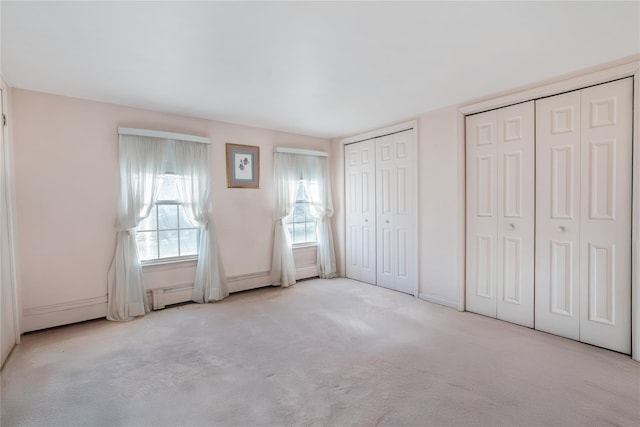 unfurnished bedroom with two closets and light colored carpet