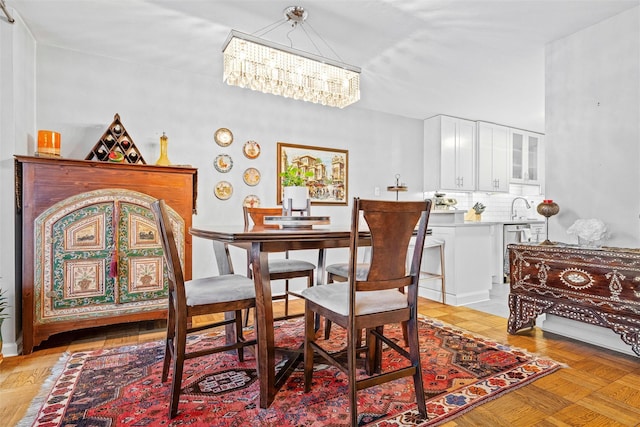 dining area featuring an inviting chandelier, sink, and light parquet flooring