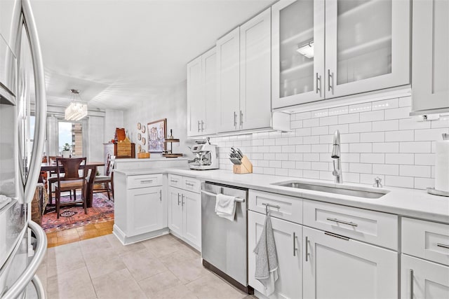 kitchen featuring stainless steel appliances, white cabinetry, sink, and backsplash