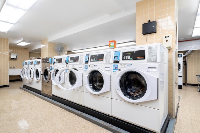 clothes washing area featuring tile walls and washer and clothes dryer