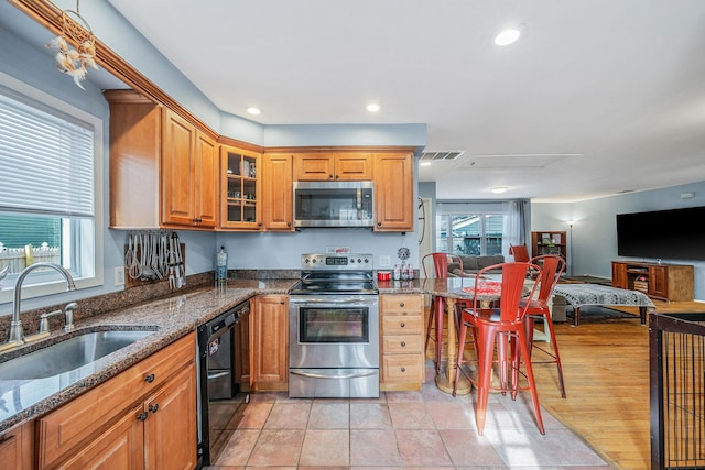 kitchen featuring a healthy amount of sunlight, appliances with stainless steel finishes, sink, and dark stone counters