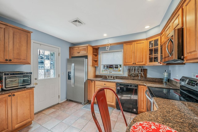 kitchen with light tile patterned flooring, stainless steel appliances, sink, and dark stone counters