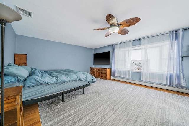 bedroom with hardwood / wood-style flooring, ceiling fan, and baseboard heating