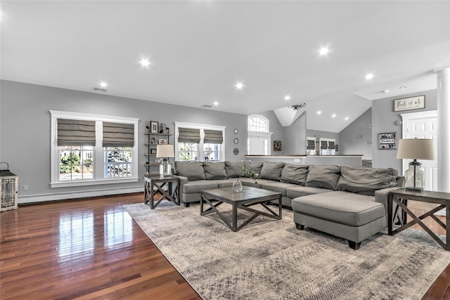 living room featuring dark wood-type flooring, decorative columns, vaulted ceiling, and baseboard heating