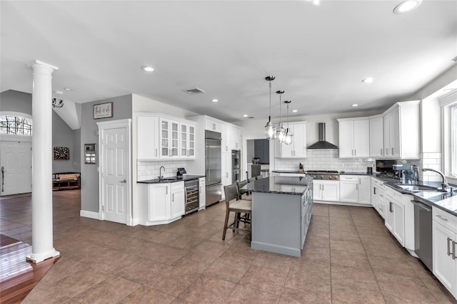 kitchen with sink, hanging light fixtures, a center island, stainless steel appliances, and wall chimney exhaust hood