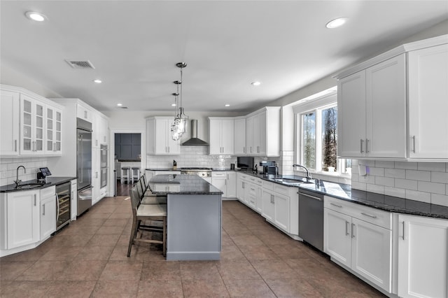 kitchen featuring pendant lighting, a breakfast bar, a kitchen island, beverage cooler, and wall chimney exhaust hood