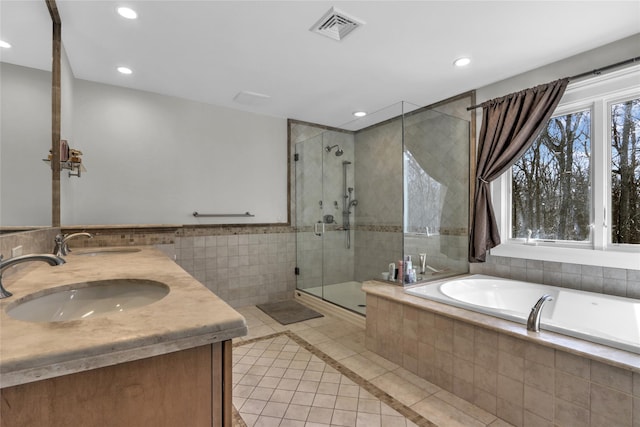 bathroom featuring independent shower and bath, vanity, tile patterned flooring, and tile walls