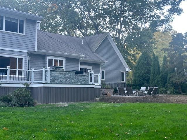 back of property featuring a wooden deck, a lawn, and a patio area