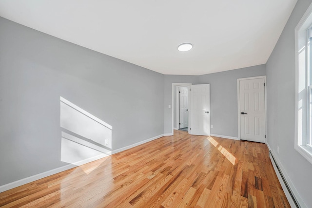 spare room with a baseboard heating unit and light wood-type flooring