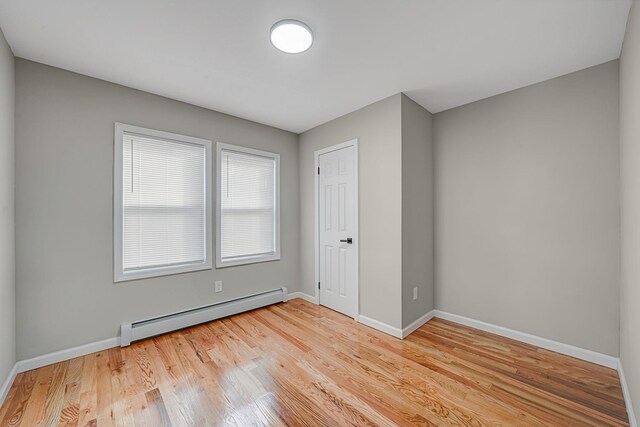 spare room featuring a baseboard radiator and light wood-type flooring