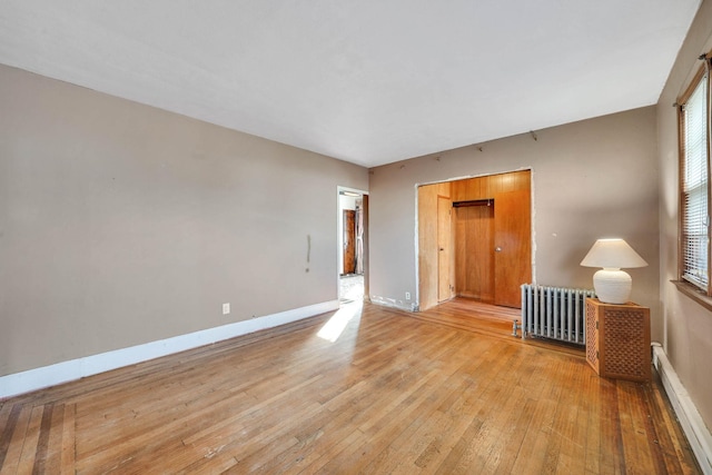 empty room with baseboard heating, radiator, and light hardwood / wood-style floors