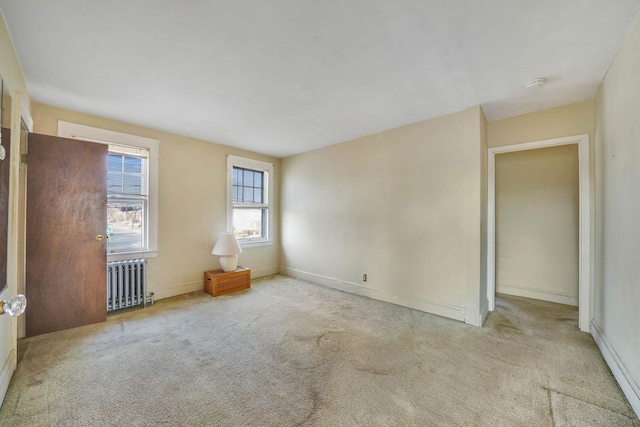 carpeted empty room with a baseboard heating unit and radiator heating unit