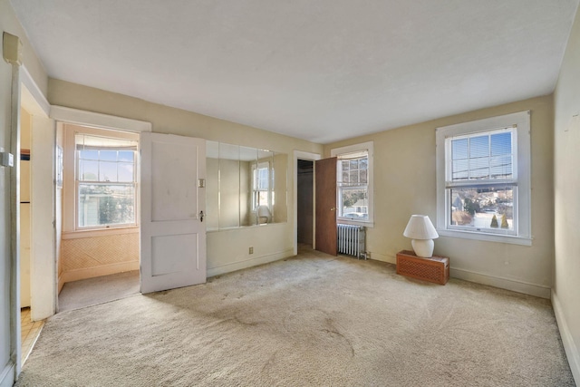 spare room featuring radiator heating unit and light colored carpet