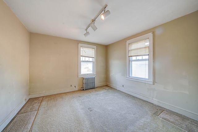 carpeted empty room with rail lighting and radiator