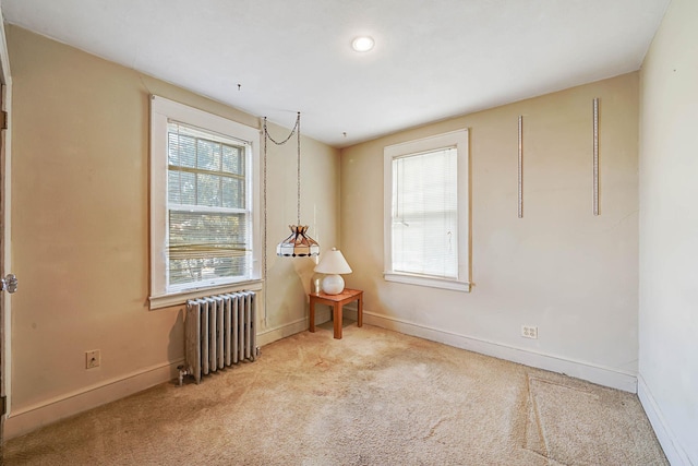 unfurnished room with radiator and light colored carpet