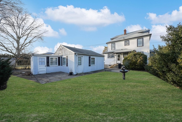 back of house with a patio and a lawn