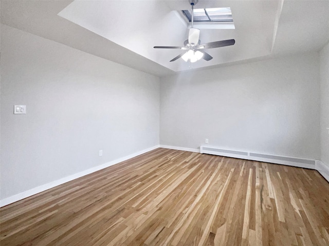 unfurnished room with hardwood / wood-style flooring, a baseboard radiator, ceiling fan, and a skylight