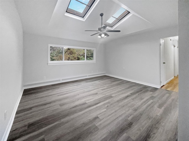 spare room with ceiling fan, wood-type flooring, and vaulted ceiling with skylight