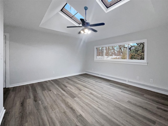 spare room featuring dark wood-type flooring, vaulted ceiling with skylight, and ceiling fan