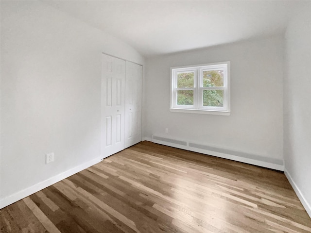 spare room with lofted ceiling, light hardwood / wood-style flooring, and baseboard heating