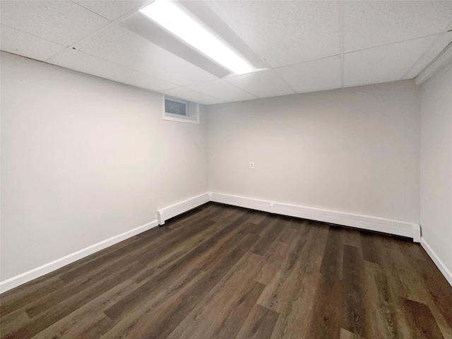 basement with dark hardwood / wood-style floors and a paneled ceiling