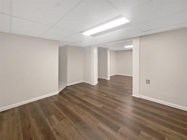 basement featuring a paneled ceiling and dark hardwood / wood-style flooring