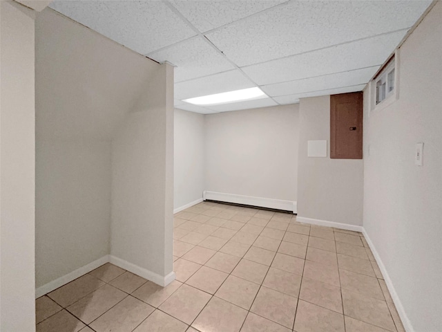 basement featuring light tile patterned flooring, a paneled ceiling, electric panel, and baseboard heating