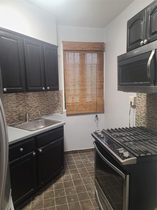 kitchen featuring stainless steel gas stove, sink, backsplash, and dark tile patterned floors