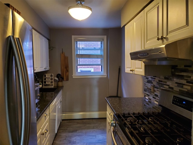 kitchen featuring appliances with stainless steel finishes, dark stone countertops, under cabinet range hood, and decorative backsplash