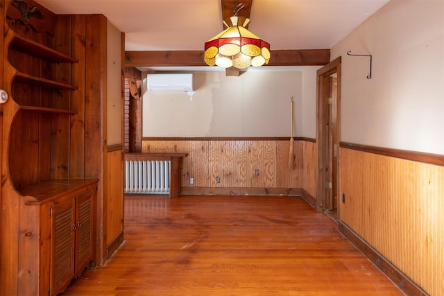 unfurnished dining area featuring radiator, wood walls, a wall unit AC, and light hardwood / wood-style floors