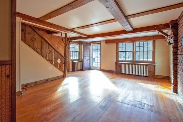 unfurnished living room with beam ceiling, radiator heating unit, and light hardwood / wood-style floors