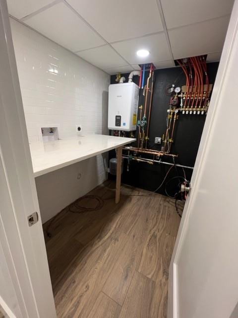 laundry room featuring washer hookup, electric dryer hookup, wood-type flooring, and tankless water heater