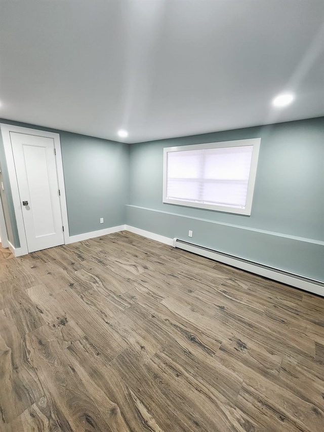 empty room with baseboard heating and hardwood / wood-style flooring