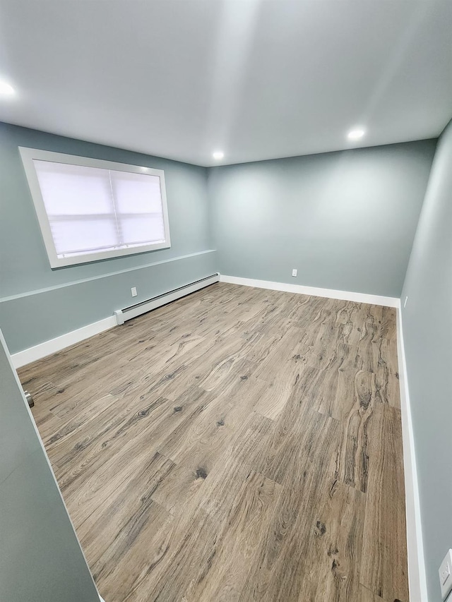 unfurnished room with a baseboard heating unit and hardwood / wood-style flooring