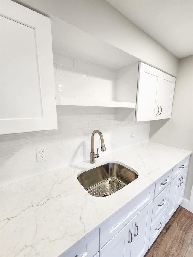 kitchen featuring white cabinetry, sink, backsplash, and light stone counters