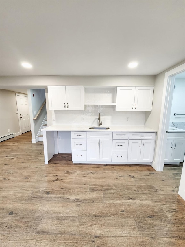 kitchen with white cabinetry, sink, backsplash, and light hardwood / wood-style floors