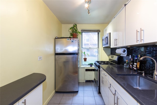 kitchen with sink, white cabinets, backsplash, light tile patterned floors, and stainless steel appliances