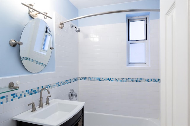 bathroom featuring tiled shower / bath combo, vanity, and tile walls