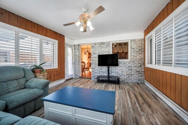 living room with hardwood / wood-style floors, wooden walls, a baseboard radiator, and ceiling fan